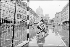 Fussballszene vor dem Tor, im Hintergrund die «Front» (Häuserzeile mit Restaurants) und das Bundeshaus