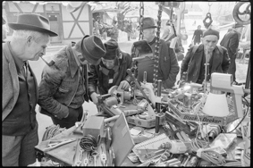 Marktbesucher bei Marktstand mit Metallwaren, im Hintergrund Marktstände in verschneitem Dorf