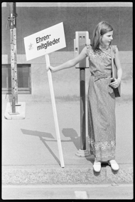 Mädchen mit einem Hinweis-Schild, darauf das Logo vom Eidg. Musikfest Biel 1976 und die Aufschrift «Ehrengäste»