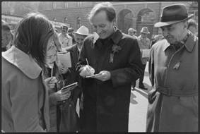 Gemeinderat Heinz Bratschi im Gespräch mit zwei Mädchen auf dem Bundesplatz, am Mantel steckt das 1. Mai-Abzeichen 1976 und eine Nelke