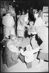 Samichlaus mit Einkaufswagen verteilt Kindern Geschenke