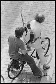 Zwei demonstrierende Musikanten auf einem Fahrrad, mit Handorgel und Gitarre