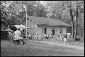 Vereinshaus des SOML (Schosshalden-Ostring-Murifeld-Leist) mit Leuten an Tischen und Bänken, Kinder am Angeln