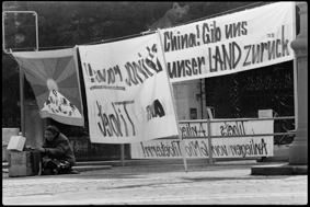Demonstrierender mit Tibet-Fahne und Transparenten