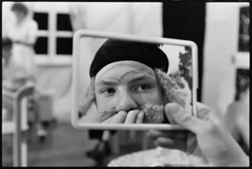 Schauspieler mit Spiegel, sich wohl als Einstein schminkend