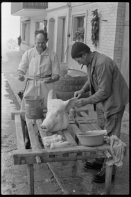 Bauer und Metzger mit Schweinekopf und -füssen
