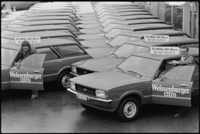 Zahlreiche parkierte Neuwagen, Werbung auf Autotüren, Firmenschilder der Th. Willy AG