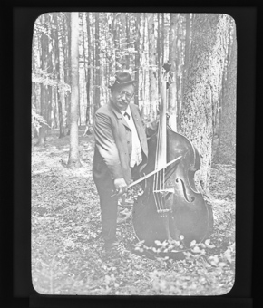 Ein Mann, Kontrabass spielend in einem Wald
