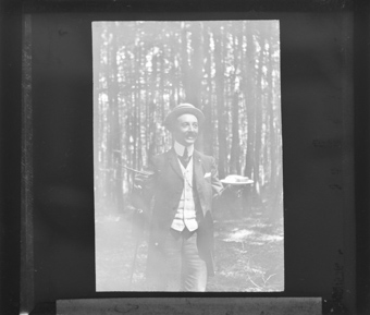 Ein Mann im Wald mit einem Teller und einem Glas in der Hand