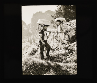 Zwei Bergbauern mit Käselaiben auf dem Weg von der Alp ins Tal