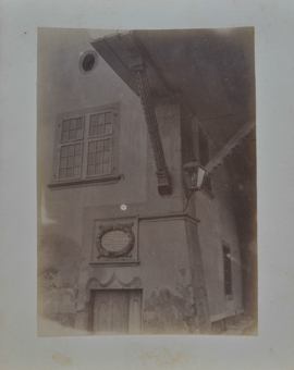 Hausecke mit geböschter Kante, geschnitzte Büge, Portal mit Kartusche, Laterne, unterteiltes Doppelfenster