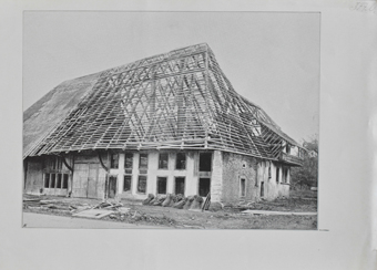 Bauernhaus mit offenem Dachstuhl, vor dem Haus Strohgarben für die Deckung