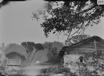 Hanglage, links Bauernhaus mit steinernem Unterbau und gezimmertem Dachstock, links Speicher in Blockbauweise