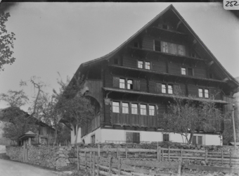 Giebelseite fünfstöckiges Wohnhaus mit gemauertem Fundament und geknicktem Satteldach Klebedächern, traufseitigen Obergeschosslauben, Garten durch Trockenmauer abgegrenzt