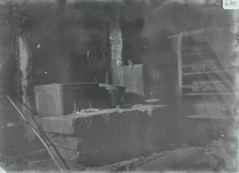 Innenaufnahme, Steine sind zu einem Art Tisch aufeinandergelegt, darauf befinden sich Kübel, an der Seitenwand ist ein Regal, in welche diverse Werkzeuge abgelegt sind