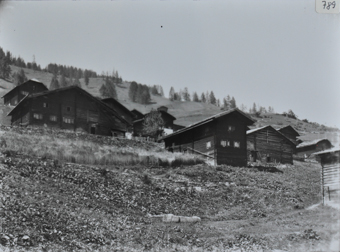 Ansicht edes Dorfes mit mehreren Bauernhäusern, Häuser aus Holz und mit Satteldach, Dorf an einem Hang gebaut