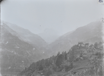 Aufnahme einer Landschaft mit Hügeln und Bergen, Tal verläuft durch das Gebirge, auf dem vorderen Hügel befinden zwei Gebäude