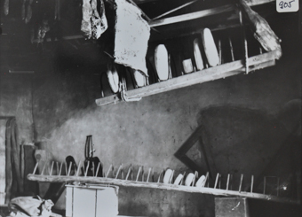 Innenaufnahme einer Räucherküche, an der Decke hängt Fleisch, Wurstwaren und Käse, weiterer Käse unten auf einem Gestell