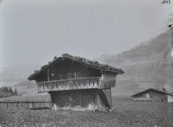 Zweistöckiges Wohnhaus aus Holz, obere Etage wie auf einem Sockel gelegen, Satteldach mit Steinen versärkt, Brennholz an der unteren Hauswand