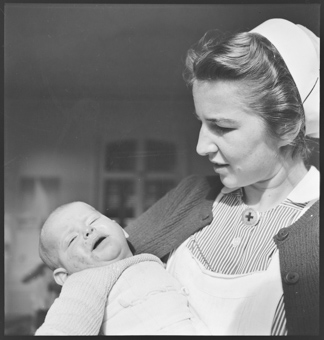 Eine Schweizer Krankenschwester mit einem Kind in den Armen