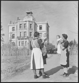 Drei Frauen vor der Maternité in Elne. Elisabeth Eidenbenz spricht mit dem Kleinkind Franziska, das von einer Gehilfin gehalten wird
