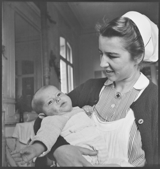 Eine Schweizer Krankenschwester mit einem Kind in den Armen
