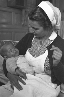 Eine Schweizer Krankenschwester mit einem Kind in den Armen