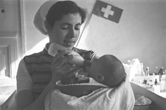 Maria García gibt einem Kleinenkind einen Schoppen mit Milch