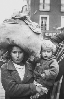 Eine Frau mit Gepäck auf dem Kopf und ihrem Kind im Arm, auf der Strasse von Le Perthus