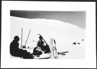 Skifahren (Lokalisierung unsicher); Zwei Skifahrer oder Skifahrerinnen sitzen im Schnee