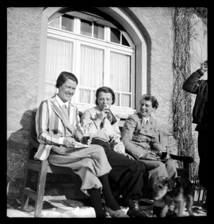 Schweiz, Engadin: Menschen; Margot Lind, Lisa von Cramm und Inge Westendarp auf einer Bank sitzend, im Vordergrund der Hund von Annemarie Schwarzenbach