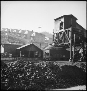USA, Scotts Run/WV: Häuser; Häuser an einem Hang, davor Eisenbahnwagen und eine Abladestelle für Kohle