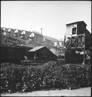 USA, Scotts Run/WV: Häuser; Häuser an einem Hang, davor Eisenbahnwagen und eine Abladestelle für Kohle