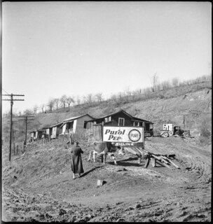 USA: Häuser; Holzhäuser, davor ein Werbeschild für Purol Pep Gasoline der Firma "The Pure Oil Company USA"