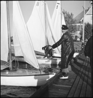 Finnland, Helsinki: Segeln; Mann auf Pier, der ein Segelschiff hält