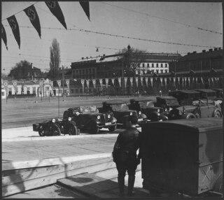 Österreich, Wien: Menschen; Im Vordergrund ein Mann in Uniform und Armeefahrzeuge, im Hintergrund Tennisplätze