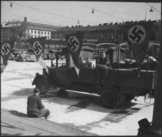Österreich, Wien: Menschen; Männer auf einem Armeelastwagen, davor hängen Hakenkreuzflaggen