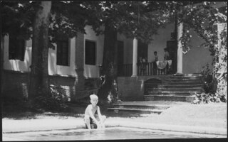 Iran, Teheran (Tehran): Menschen; Ein Knabe sitzt an einem Schwimmbecken, im Hintergrund ein Gebäude