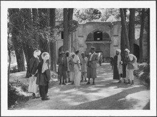 Afghanistan, Karokh: Schrein; Ella Maillart umgeben von einer Gruppe Männer, im Hintergrund Eingang zum Schrein