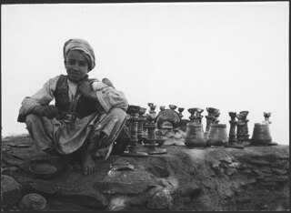 Next to the potter's apprentice one can see two or three tall oil lamps as they look when finished. The boy sits on top of the kiln. | Serie 14 | Bild 4