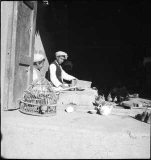 Afghanistan, Ghazni (Ghazna): Menschen; Männer mit einem Knaben sitzend in einem Haus, davor ein Vogelkäfig und Teegeschirr
