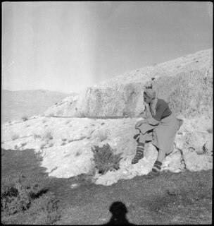 Afghanistan, Haibak (Samangan, Aybak or Aibak): Menschen (Lokalisierung unsicher); Eine sitzende Frau auf einem Abhang, im Hintergrund Berge