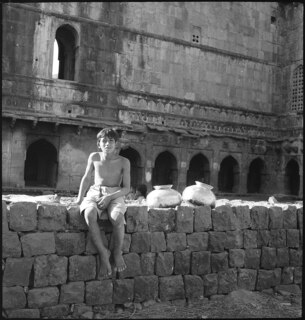 Britisch-Indien, Mandu (Mandav): Menschen; Ein sitzender Knabe auf einer Mauer vor einem Gebäude