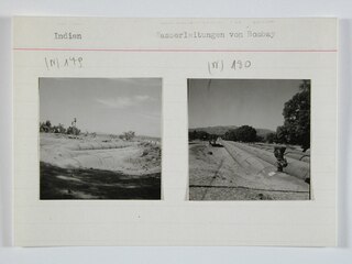 Britisch-Indien, Bombay (Mumbai): Landschaft; Karteikarte: Vier nebeneinanderliegende Rohre neben einem Gleis und einer Strasse, zum Teil zugedeckt mit Erde
