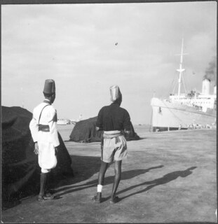 Italienisch-Ostafrika, Massana (Massawa, Massaua): Hafen; Zwei Männer in Uniform am Quai vor dem Schiff