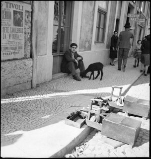 Portugal, Lissabon (Lisboa): Strassenszenen; Ein Mann mit einem Schaff sitzt auf einer Türschwelle, im Vordergrund Schuhputzmaterial