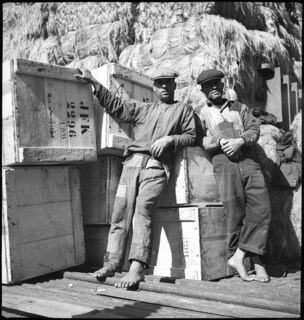 Portugal, Lissabon (Lisboa): Hafen; Zwei Männer vor Kisten mit der Aufschrift JFK, dahinter ein Berg Baumwolle