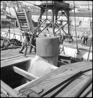 Portugal, Lissabon (Lisboa): Schiff Sud; Männer laden aus einem Behälter, der an einem Kran hängt, Ware in ein Schiff