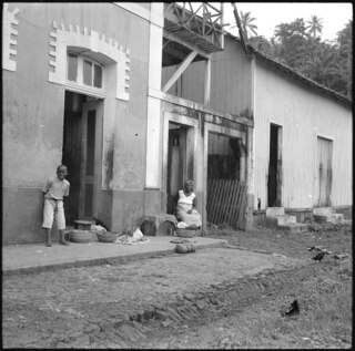 Portugal, San Thomé (São Tomé und Príncipe): Menschen; Frau sitzend vor Hauseingang mit Knaben stehend