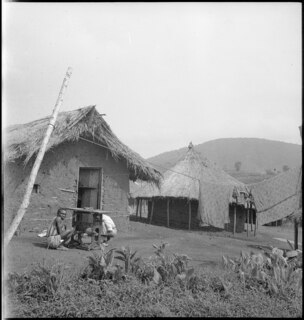 Belgisch-Kongo, Butembo: Dorfansicht; Zwei Hütten aus Lehm und Stroh mit einer Wäscheleine im Vordergrund